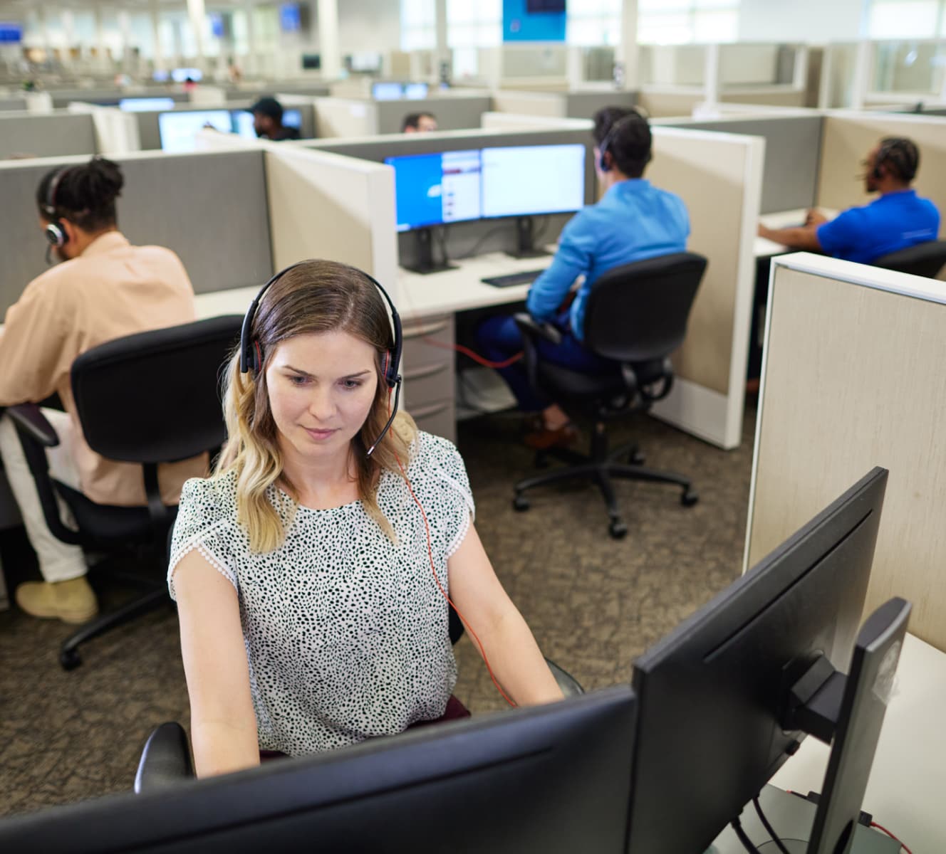 ADT customer service rep in the ADT call center typing on her computer and troubleshooting with a customer on her headset ADT customer service rep in the ADT call center typing on her computer and troubleshooting with a customer on her headset