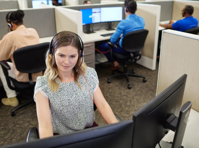 ADT customer service rep in the ADT call center typing on her computer and troubleshooting with a customer on her headset ADT customer service rep in the ADT call center typing on her computer and troubleshooting with a customer on her headset