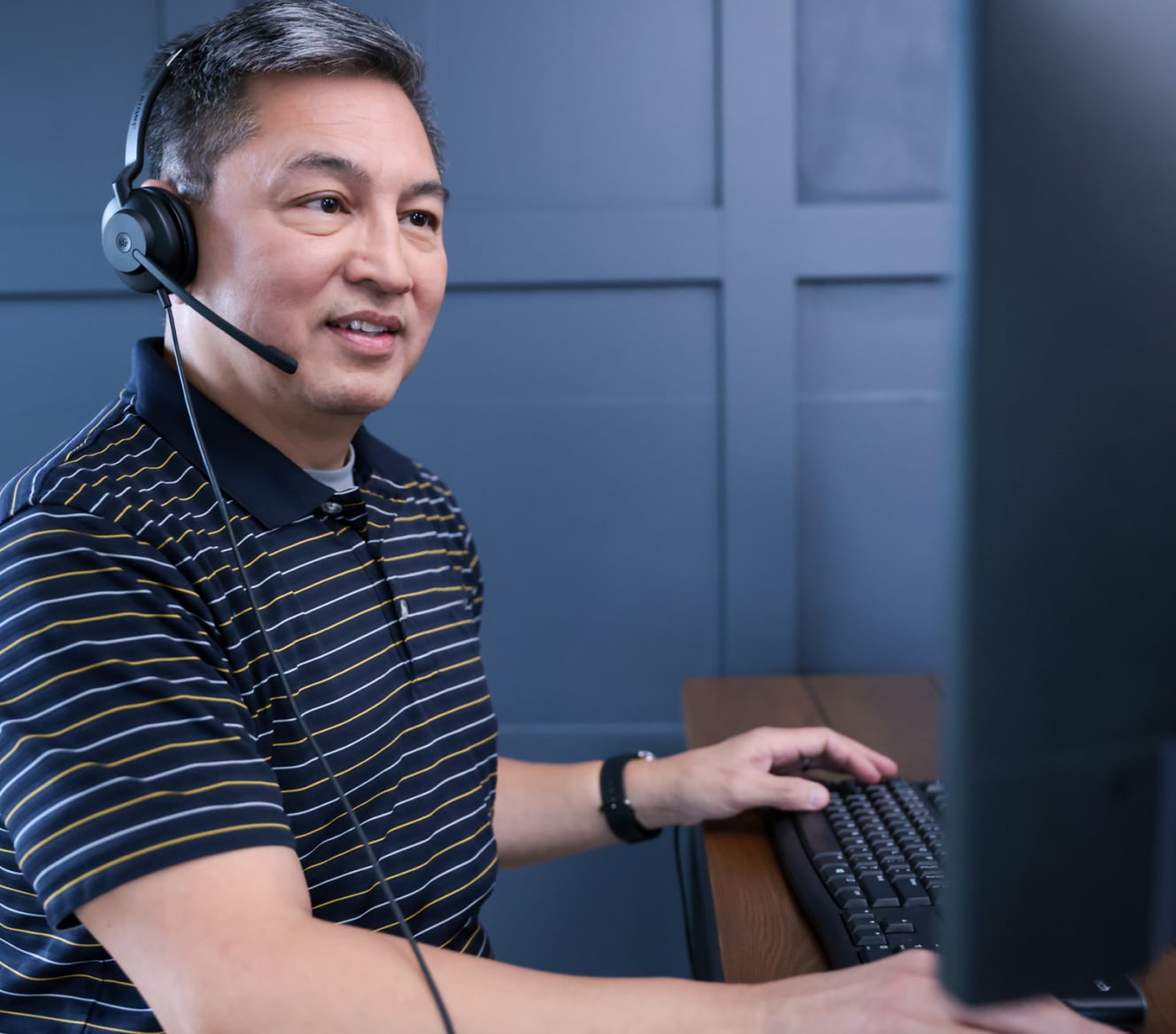 ADT customer service rep typing on his computer and troubleshooting with a customer on his headset ADT customer service rep typing on his computer and troubleshooting with a customer on his headset