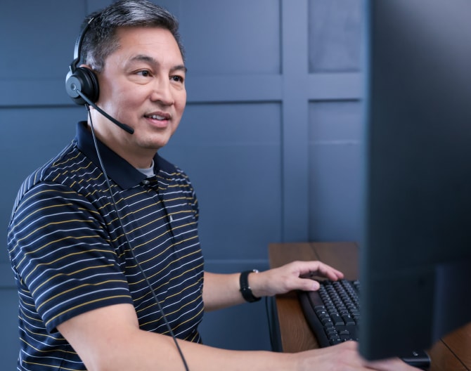 ADT customer service rep typing on his computer and troubleshooting with a customer on his headset ADT customer service rep typing on his computer and troubleshooting with a customer on his headset