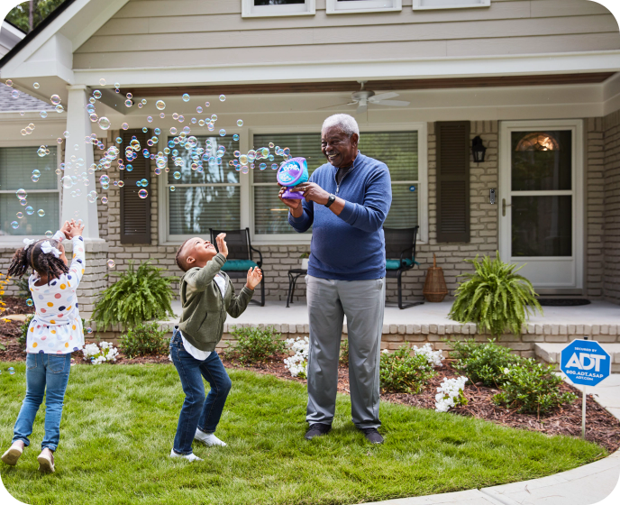 Family in front of ADT protected home playing with bubbles Family in front of ADT protected home playing with bubbles