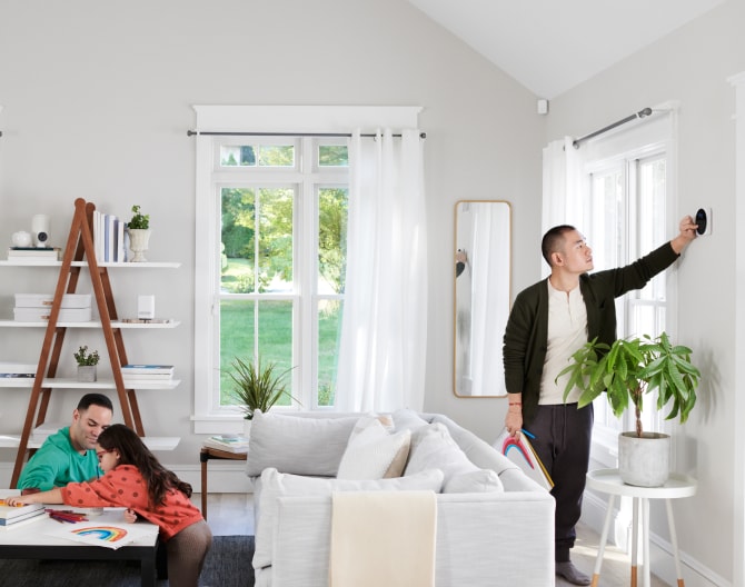 Family sitting in their living room while someone adjusts the Google Nest Cam (Indoor) Family sitting in their living room while someone adjusts the Google Nest Cam (Indoor)