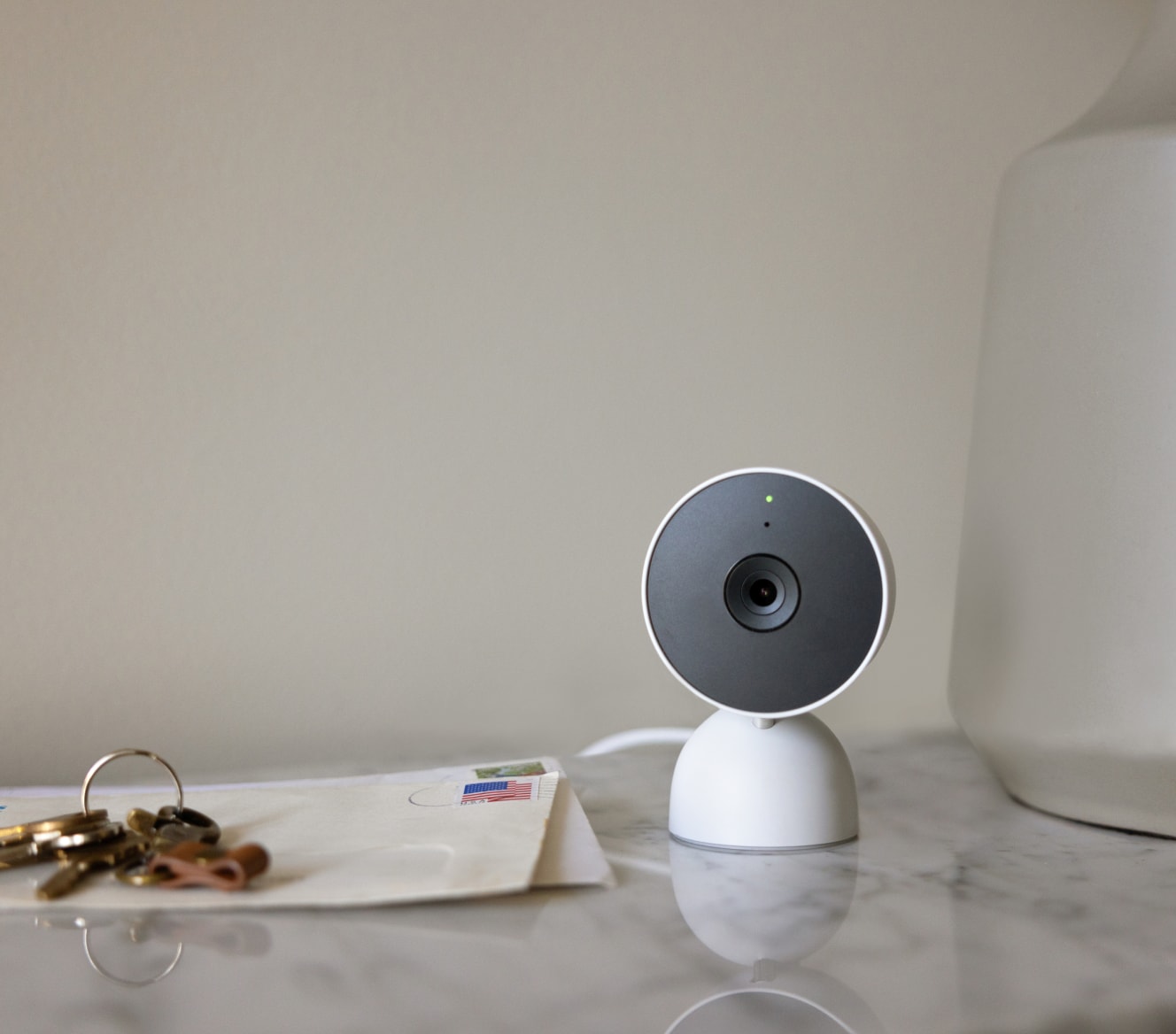 Google Nest Cam (Indoor) on a table next to house keys and mail Google Nest Cam (Indoor) on a table next to house keys and mail