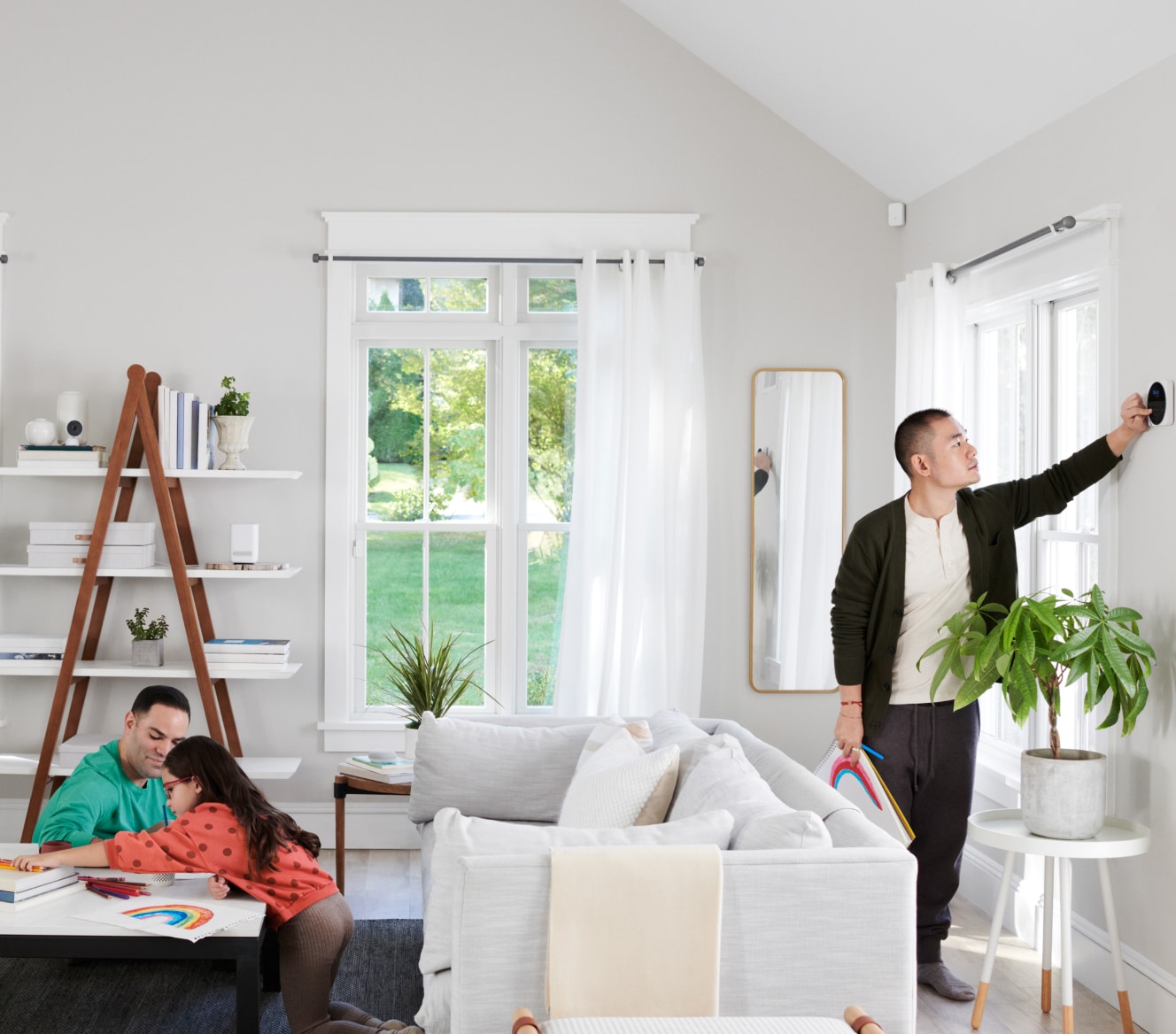 Family sitting in their living room while someone adjusts the Google Nest Cam (Indoor) Family sitting in their living room while someone adjusts the Google Nest Cam (Indoor)