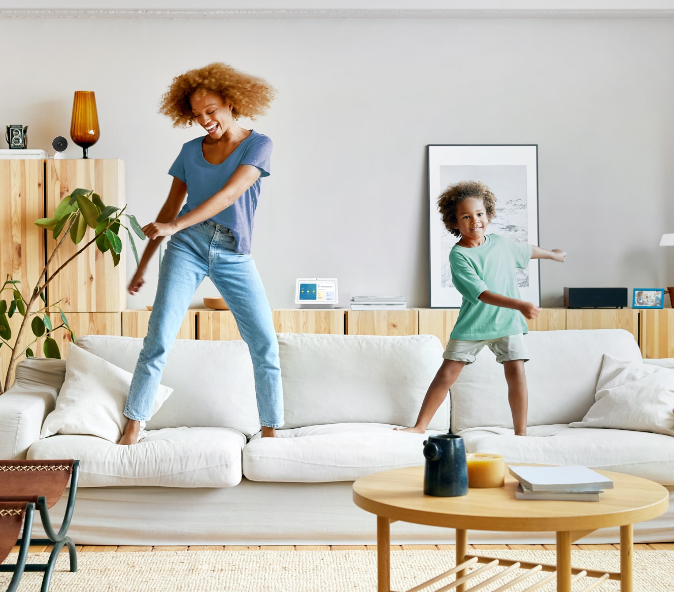 Google Nest Hub 2nd Gen on a shelf while a mother and son dance on their couch Google Nest Hub 2nd Gen on a shelf while a mother and son dance on their couch