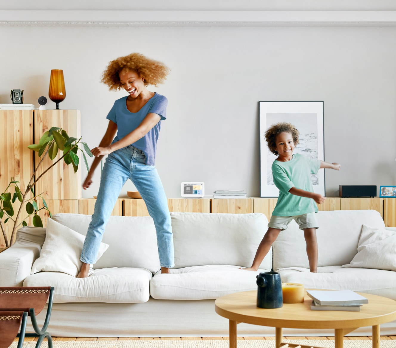 Google Nest Hub 2nd Gen on a shelf while a mother and son dance on their couch Google Nest Hub 2nd Gen on a shelf while a mother and son dance on their couch