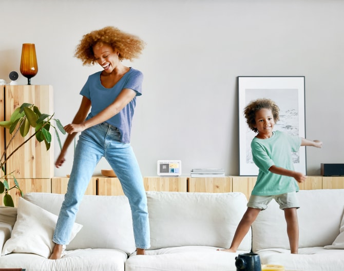 Google Nest Hub 2nd Gen on a shelf while a mother and son dance on their couch Google Nest Hub 2nd Gen on a shelf while a mother and son dance on their couch