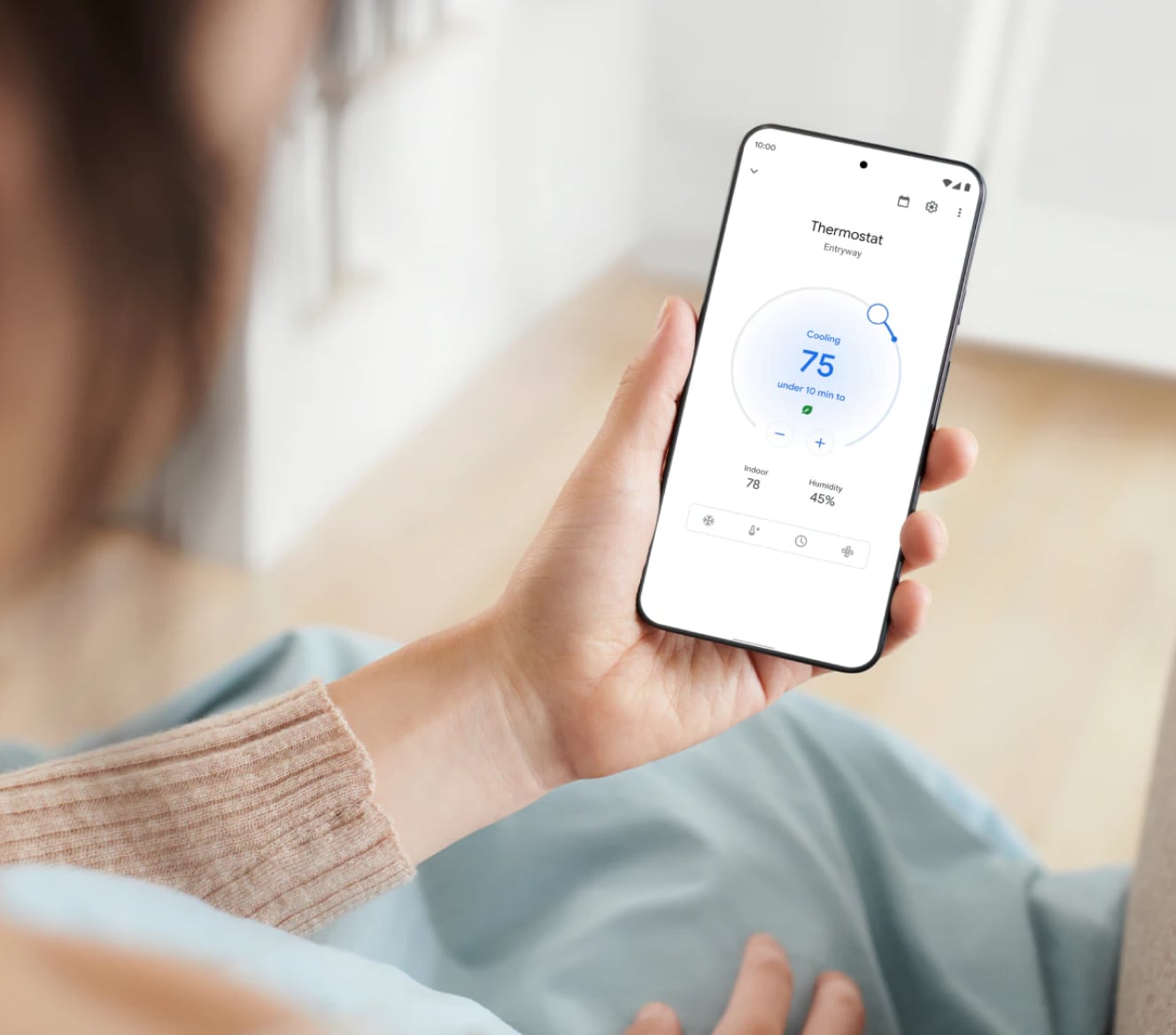 Woman adjusting her Google Nest Learning Thermostat using her cell phone Woman adjusting her Google Nest Learning Thermostat using her cell phone