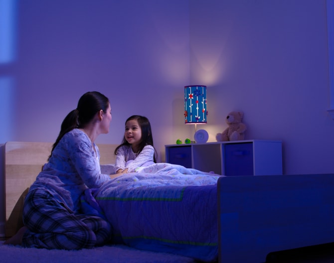 Women tucking in her child while the Google Nest Learning Thermostat sets the temperature Women tucking in her child while the Google Nest Learning Thermostat sets the temperature