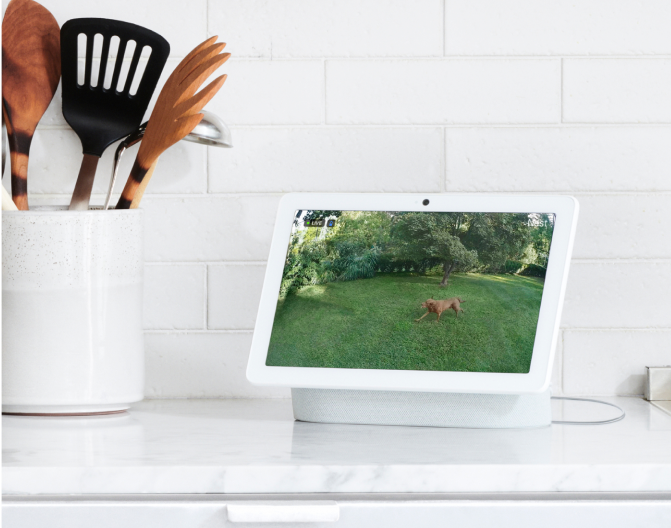 Google Nest Hub Max on a kitchen counter next to kitchen utensils Google Nest Hub Max on a kitchen counter next to kitchen utensils