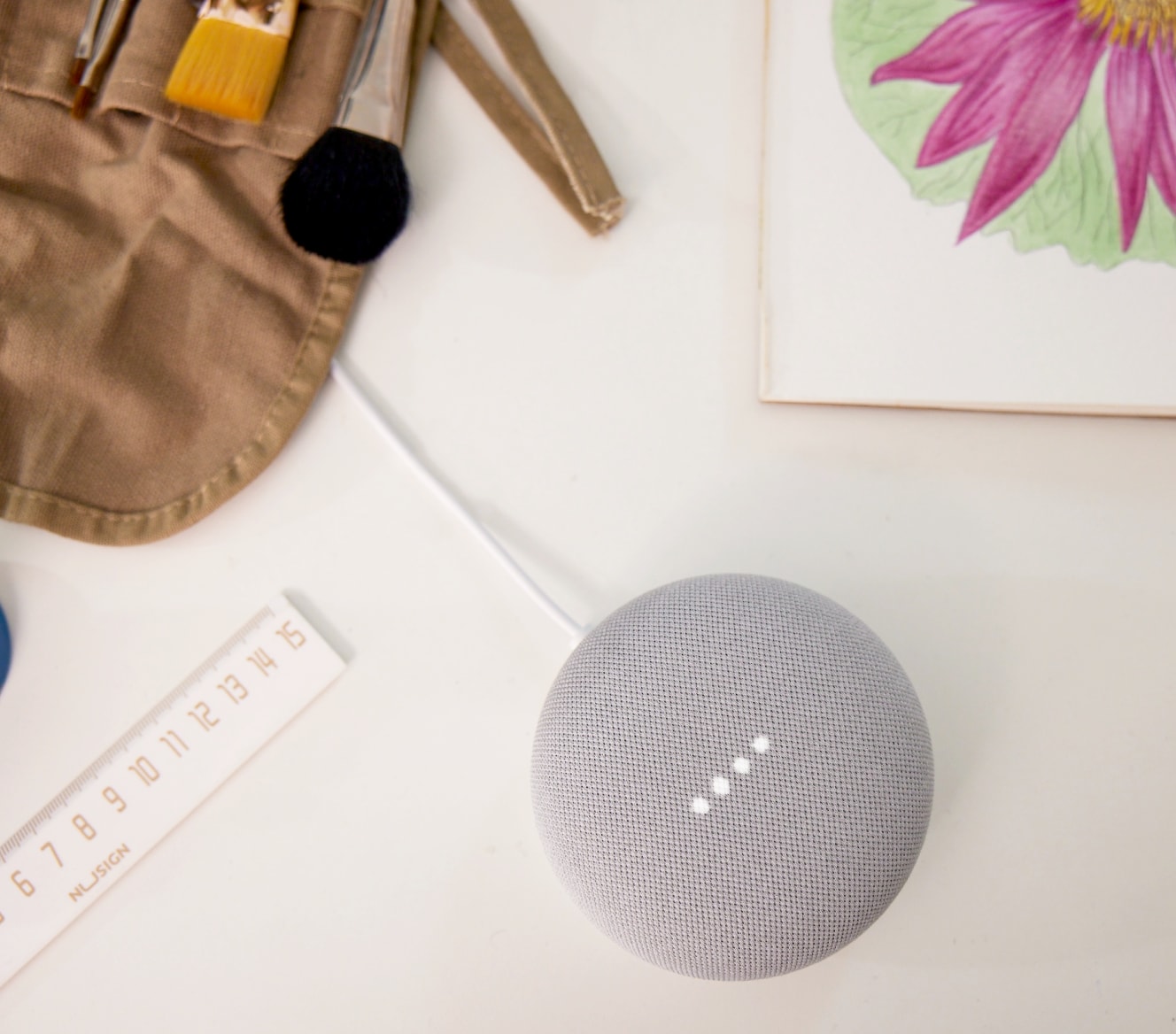 Google Nest Mini on a table with paint brushes and a ruler Google Nest Mini on a table with paint brushes and a ruler