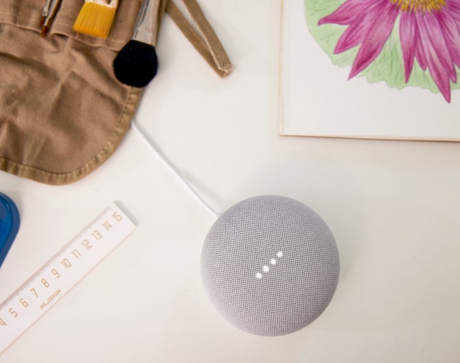 Google Nest Mini on a table with paint brushes and a ruler Google Nest Mini on a table with paint brushes and a ruler
