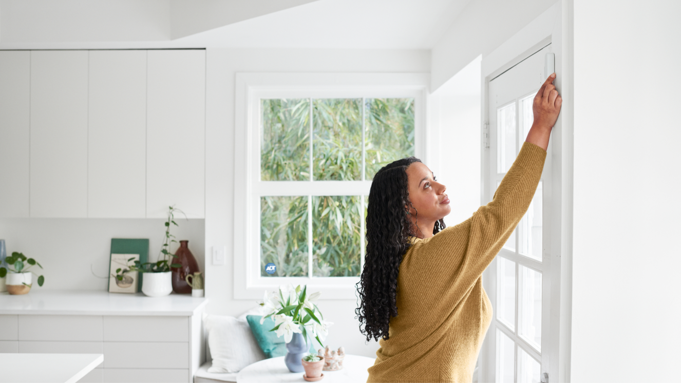 Woman self installing a window sensor in her home Woman self installing a window sensor in her home