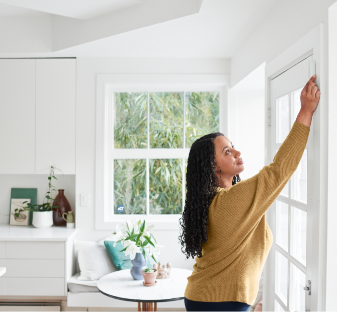 Woman self installing a window sensor in her home Woman self installing a window sensor in her home