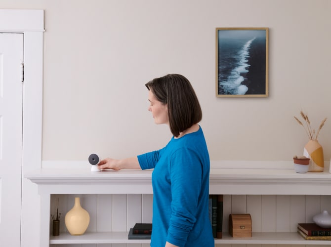Women adjusting indoor camera in her home Women adjusting indoor camera in her home
