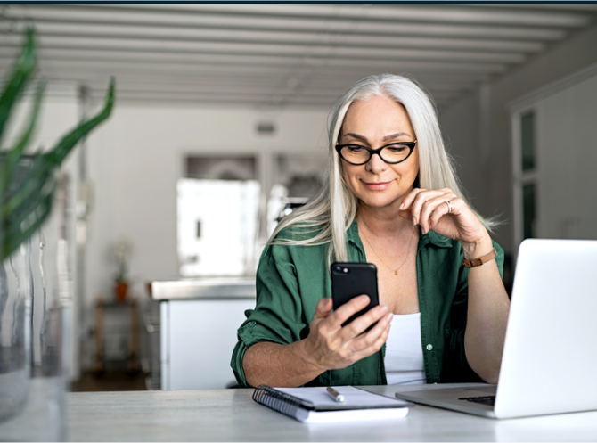 Woman looking at her ADT app on her phone in her home Woman looking at her ADT app on her phone in her home