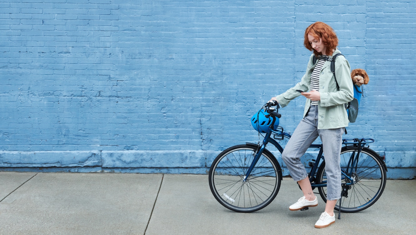 Women on a bike using the ADT+ app on her phone Women on a bike using the ADT+ app on her phone