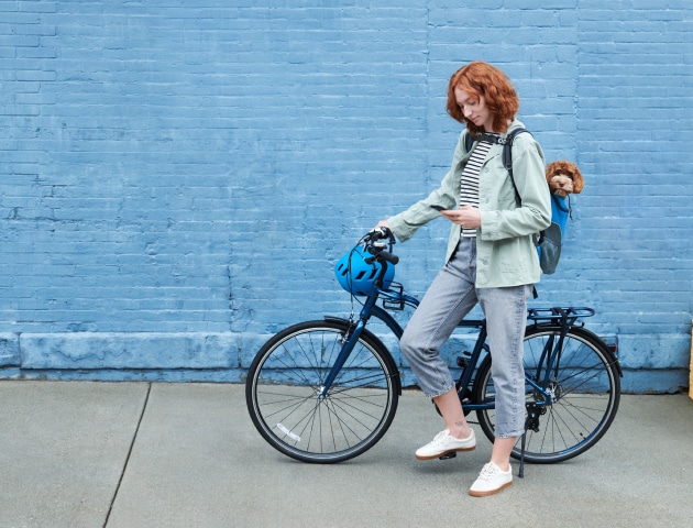 Women on a bike using the ADT+ app on her phone Women on a bike using the ADT+ app on her phone